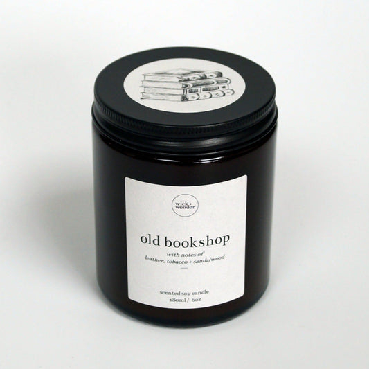 'Old Bookshop' book scented soy candle in amber jar with black lid and illustration. The perfect book lover gift for readers. Handmade vegan, soy candle by Wick + Wonder.